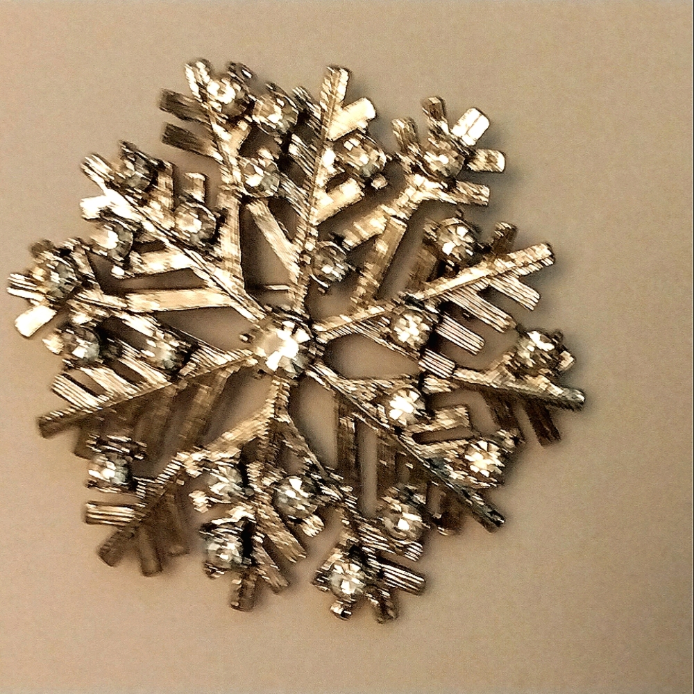 Gold plated & cubic zirconia snowflake pin. It's whimsical & captivating.